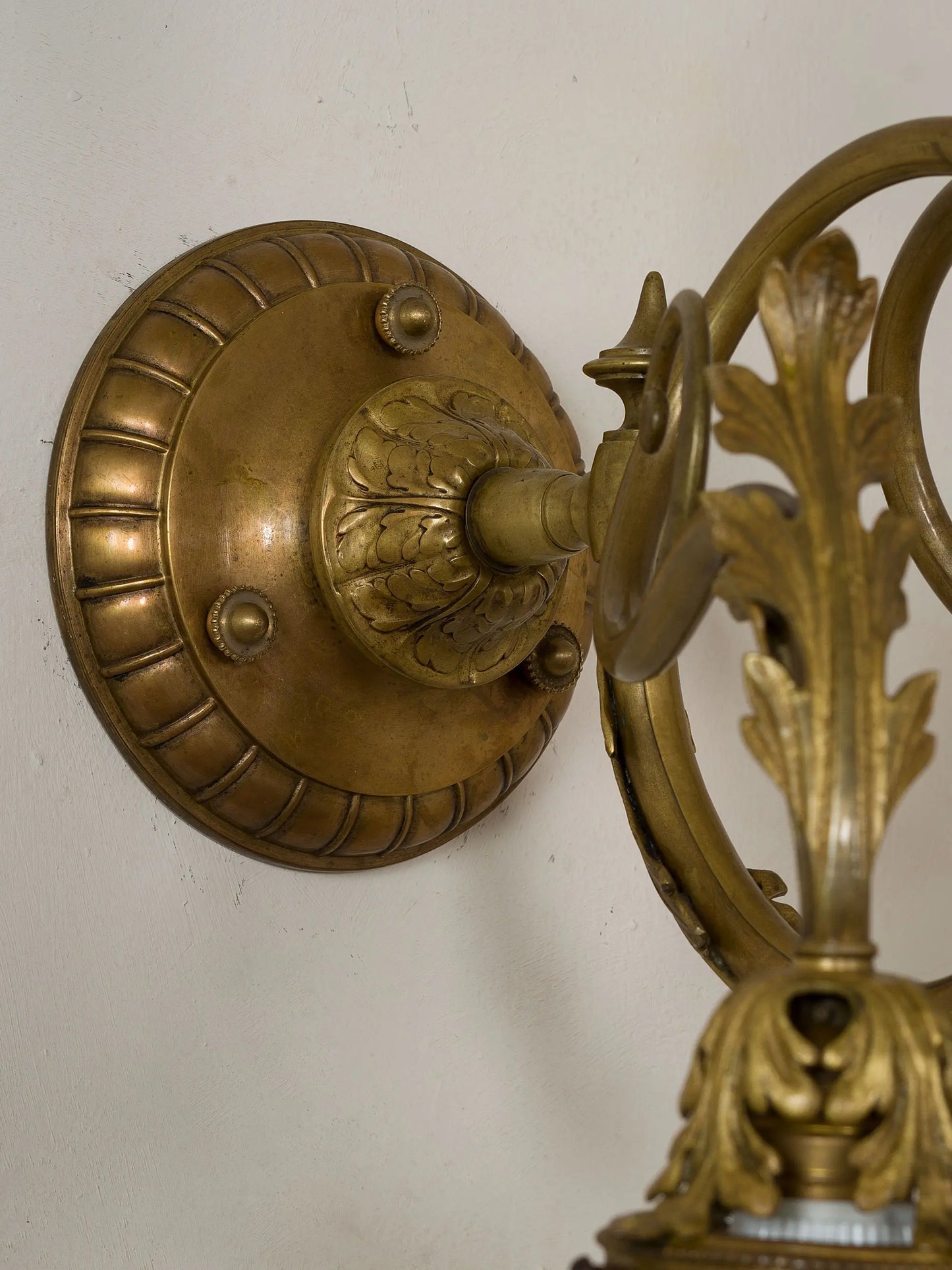Dettaglio del decoro floreale scolpito nella base del braccio in bronzo dell’applique. | Lo Stile Italiano