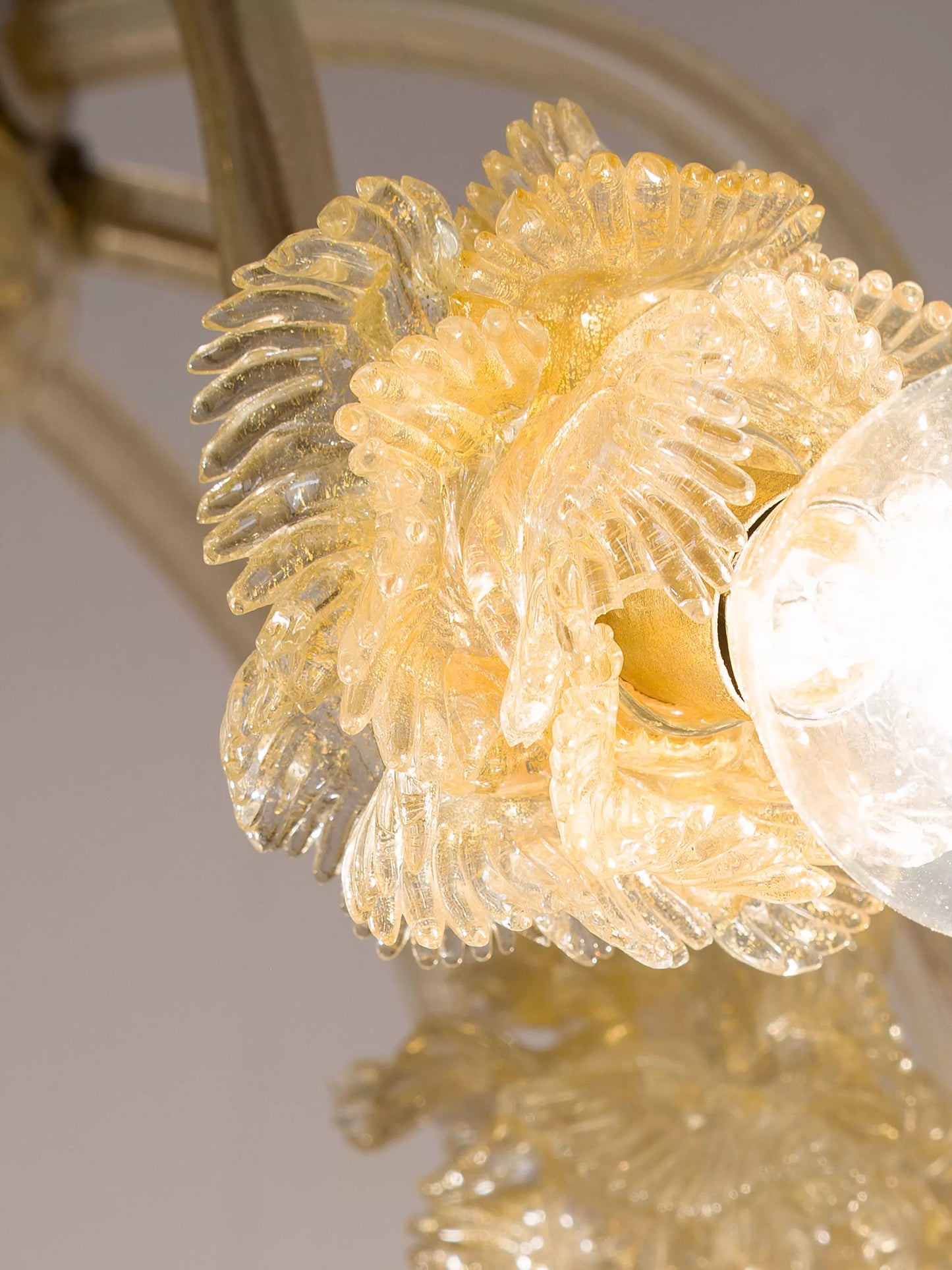 Dettaglio dei fiori in vetro soffiato con riflessi dorati su lampadario Murano vintage.| Lo Stile Italiano