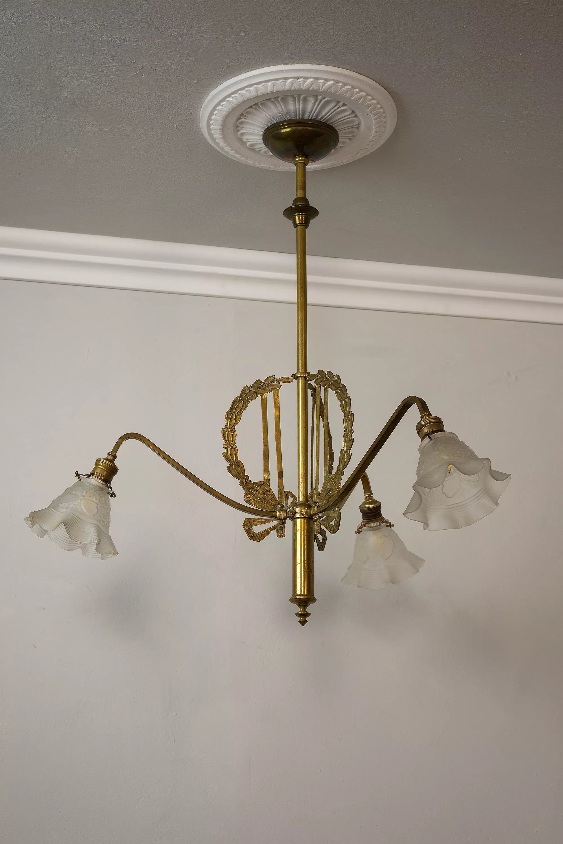 Lampadario Liberty con fregio a forma di corona di alloro e paralumi in vetro opalino a forma di fazzoletto, decorati con farfalle.| Lo Stile Italiano