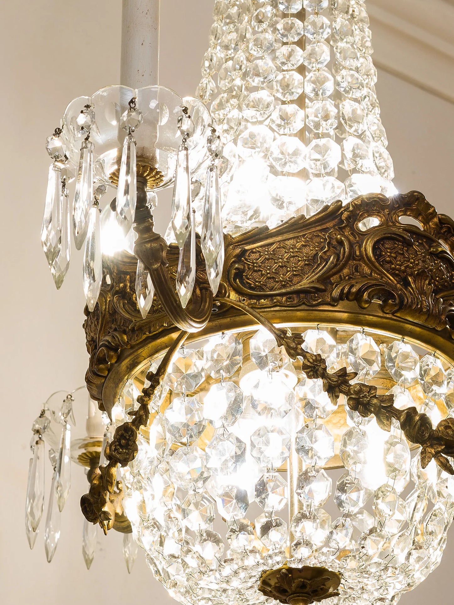 Dettaglio della parte centrale del lampadario con la corona in bronzo cesellato e gocce di cristallo pendenti. | Lo Stile Italiano