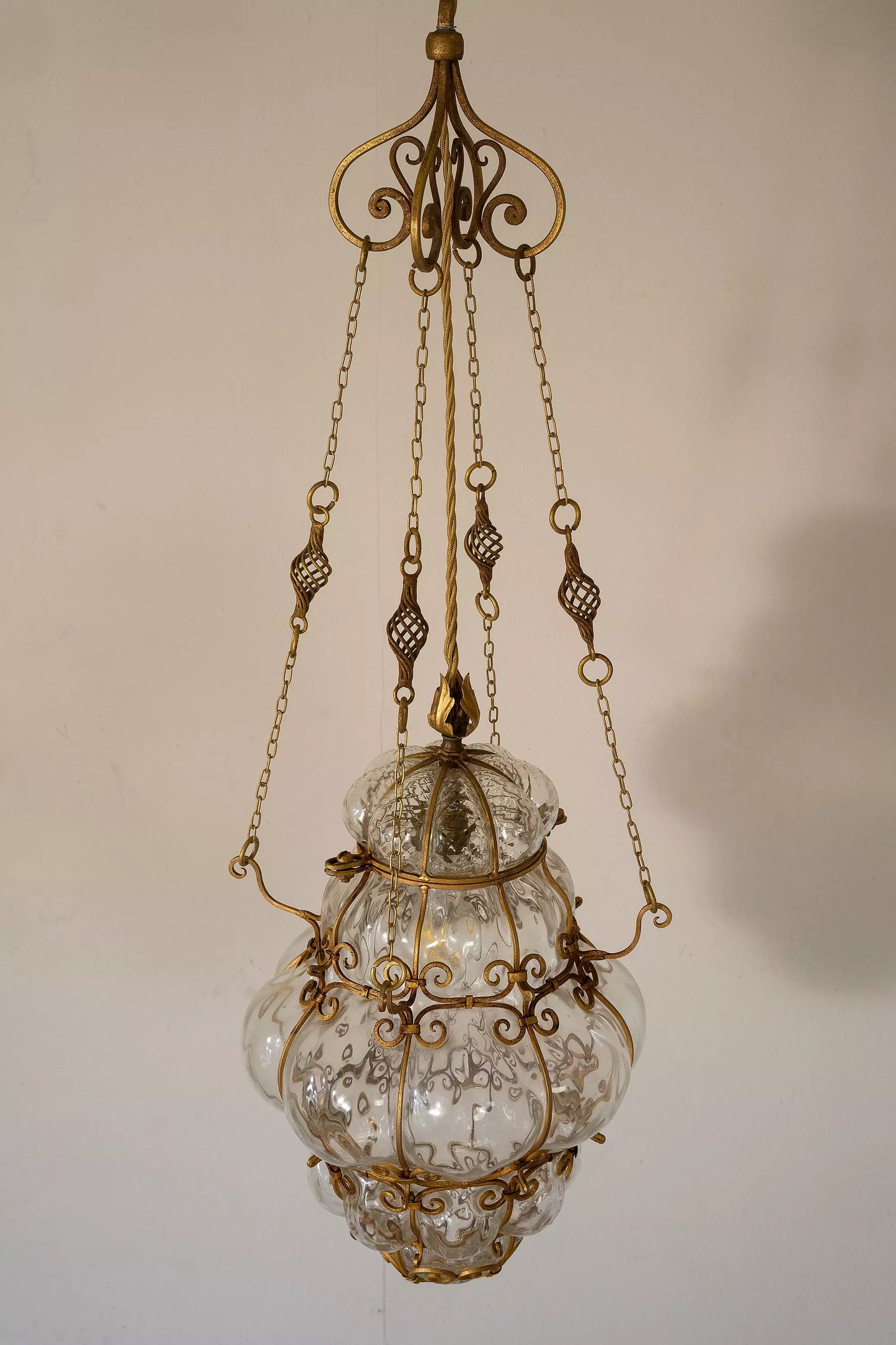 Lampadario antico in vetro di Murano, arricchito riccioli e intricati motivi in ferro battuto.| Lo Stile Italiano
