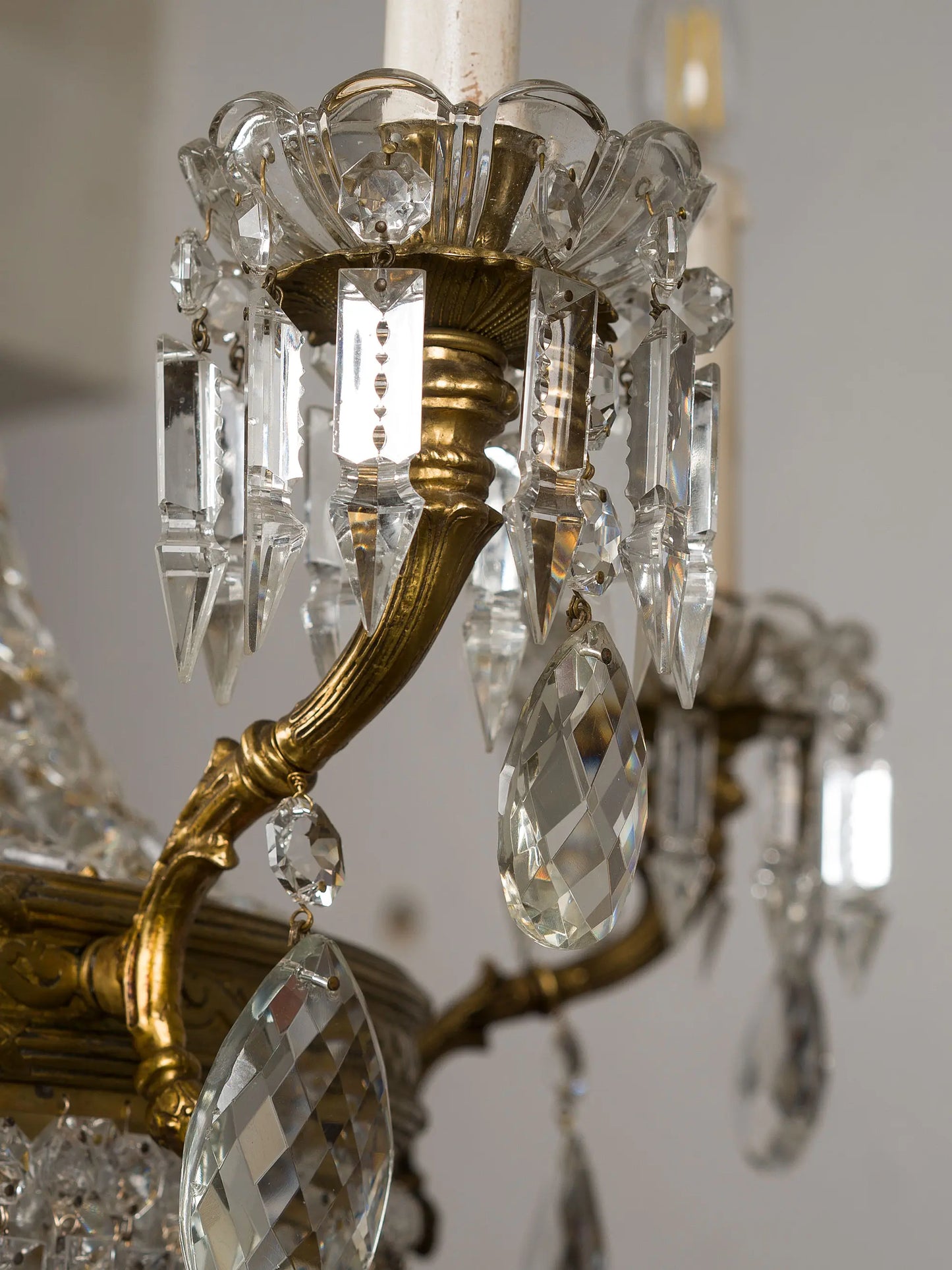 Dettaglio dei bracci in bronzo dorato e delle candele con gocce di cristallo pendenti di un lampadario d'epoca italiano | Lo Stile Italiano