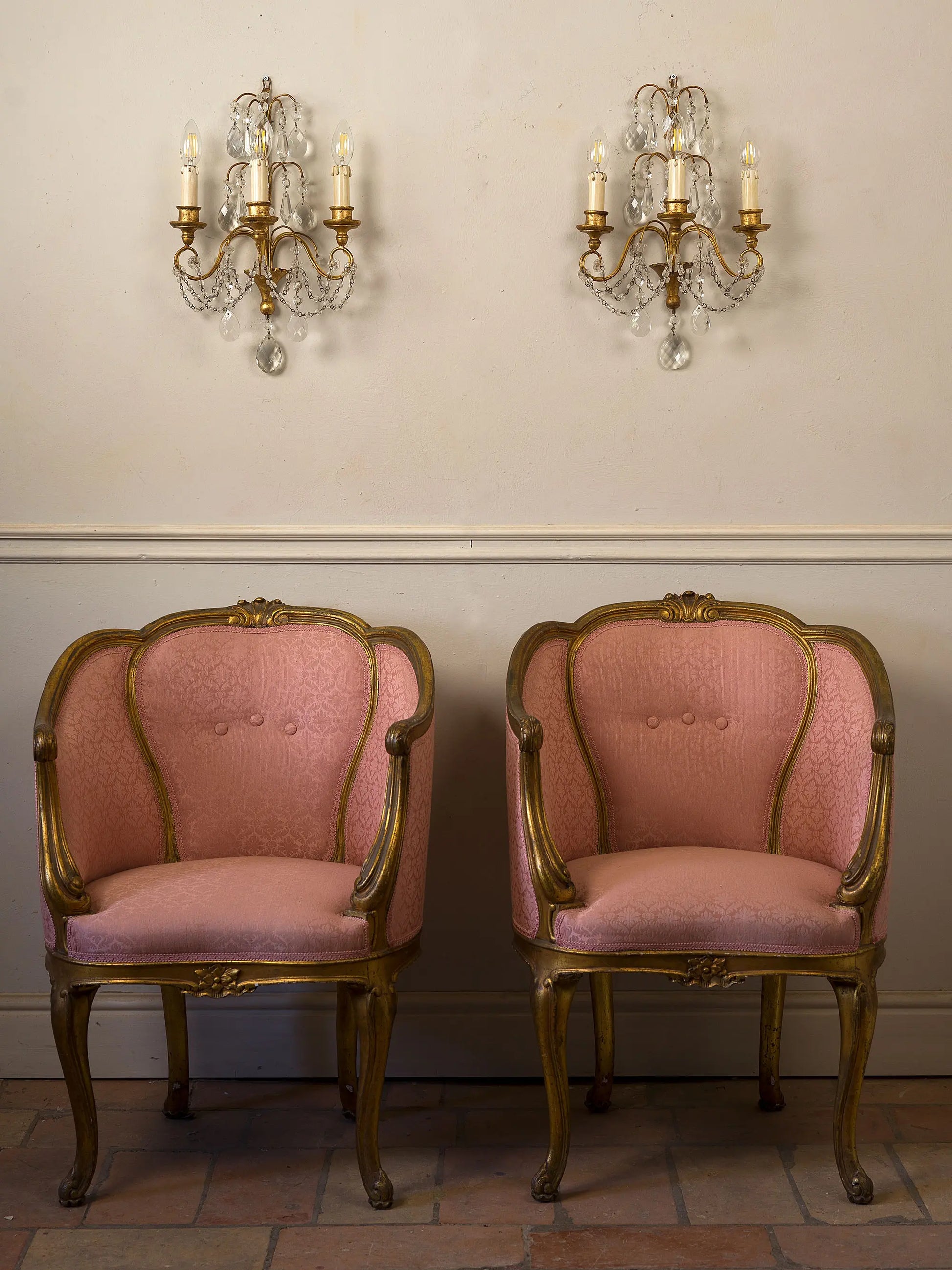 Coppia di applique decorative con dettagli dorati e cristalli, fotografate con coppia di poltroncine aniche | Lo Stile Italiano