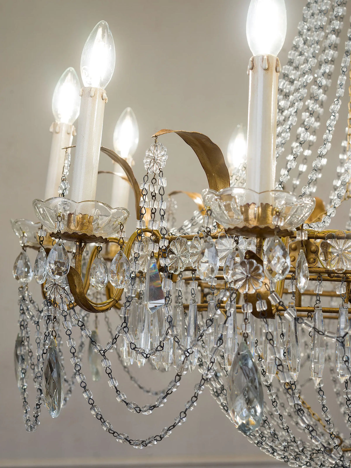 Dettaglio delle luci del lampadario con coppe in vetro, cristalli pendenti e ferro dorato | Lo Stile Italiano 