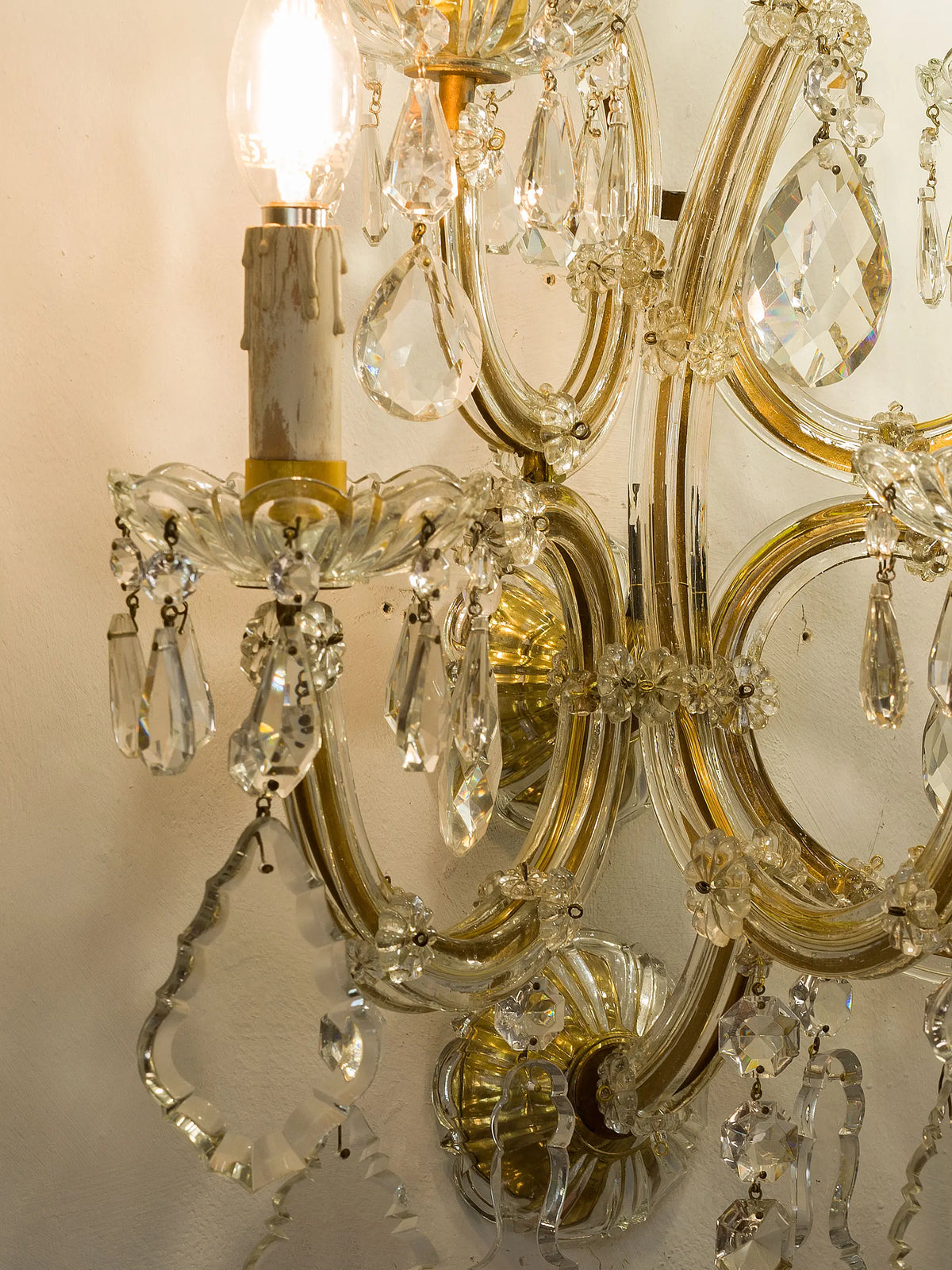 Dettaglio di applique vintage con volute dorate, placche e gocce in cristallo | Lo Stile Italiano