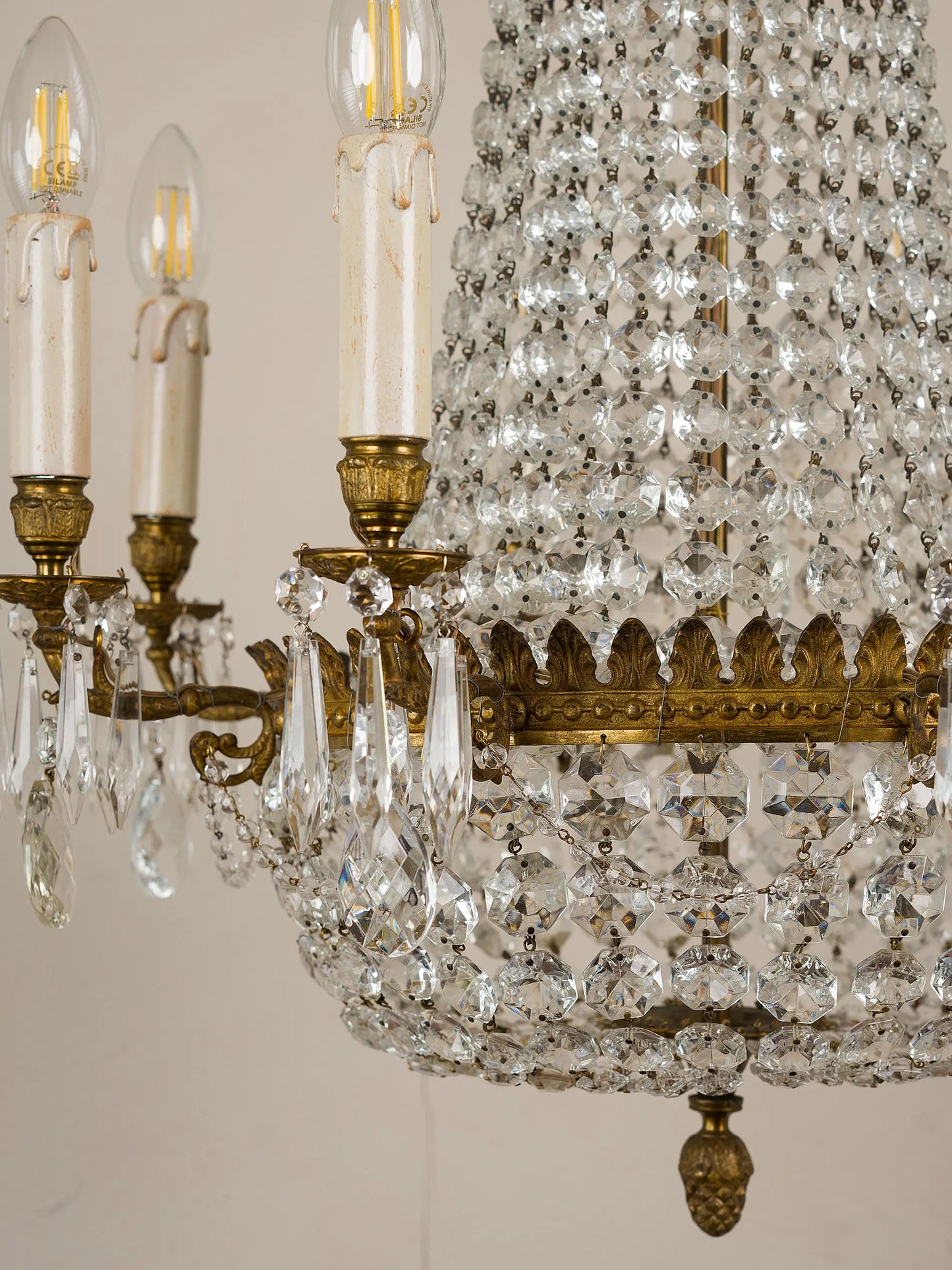 Empire-style chandelier in balloon shape, made in Italy in the 1940s.  
The brass structure is composed of chains of ground glass arranged progressively to form the typical basket structure. Eight internal arms support wooden candles decorated with crystal pendants. | Lo Stile Italiano