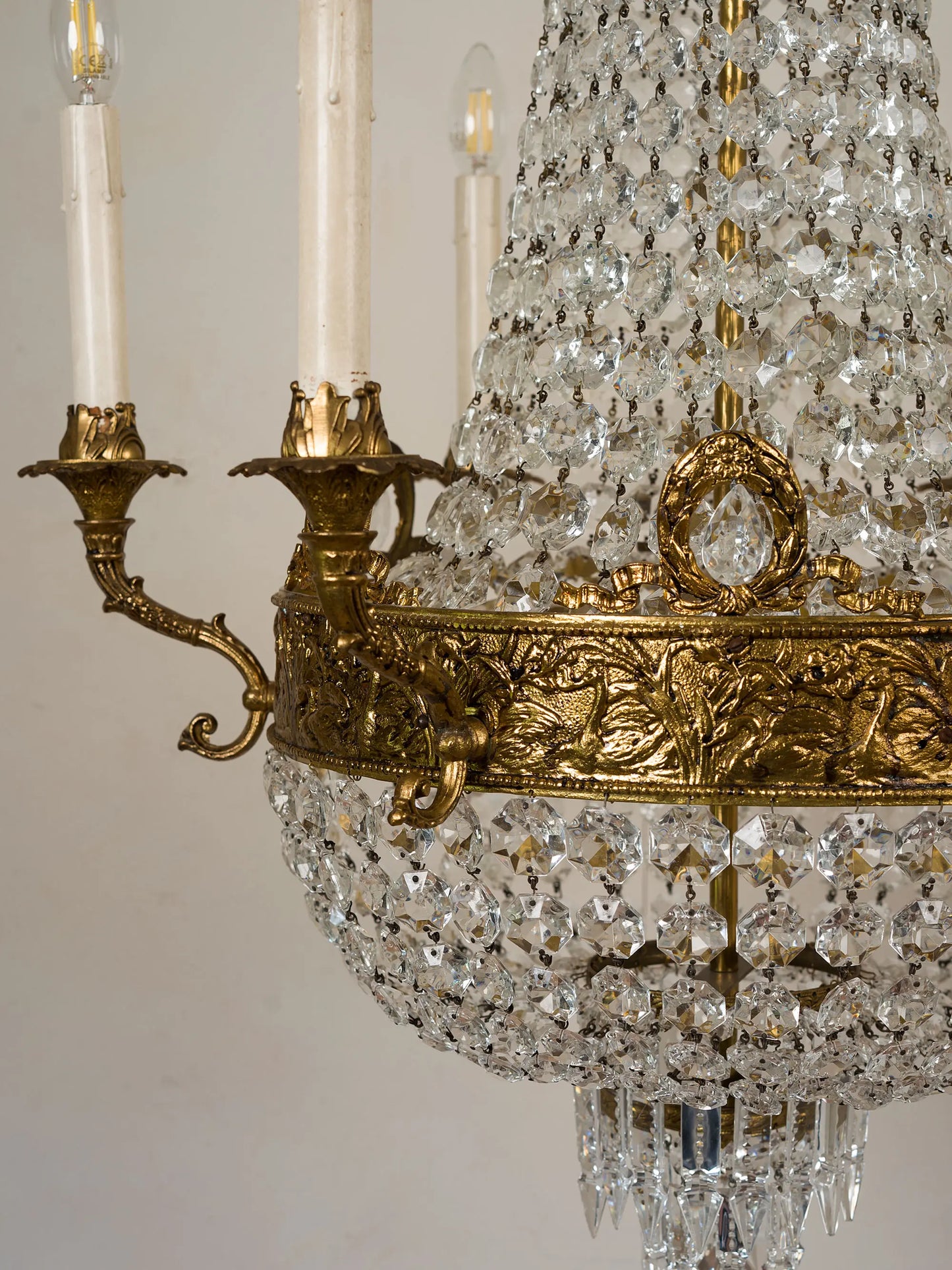 Dettaglio ravvicinato della decorazione in bronzo dorato con pendente centrale in cristallo del lampadario classico italiano | Lo Stile Italiano