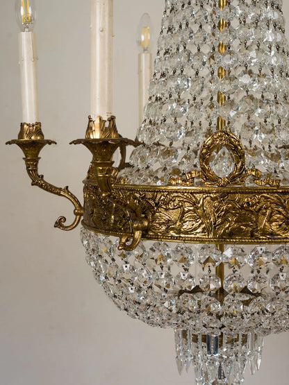 Dettaglio ravvicinato della decorazione in bronzo dorato con pendente centrale in cristallo del lampadario classico italiano | Lo Stile Italiano