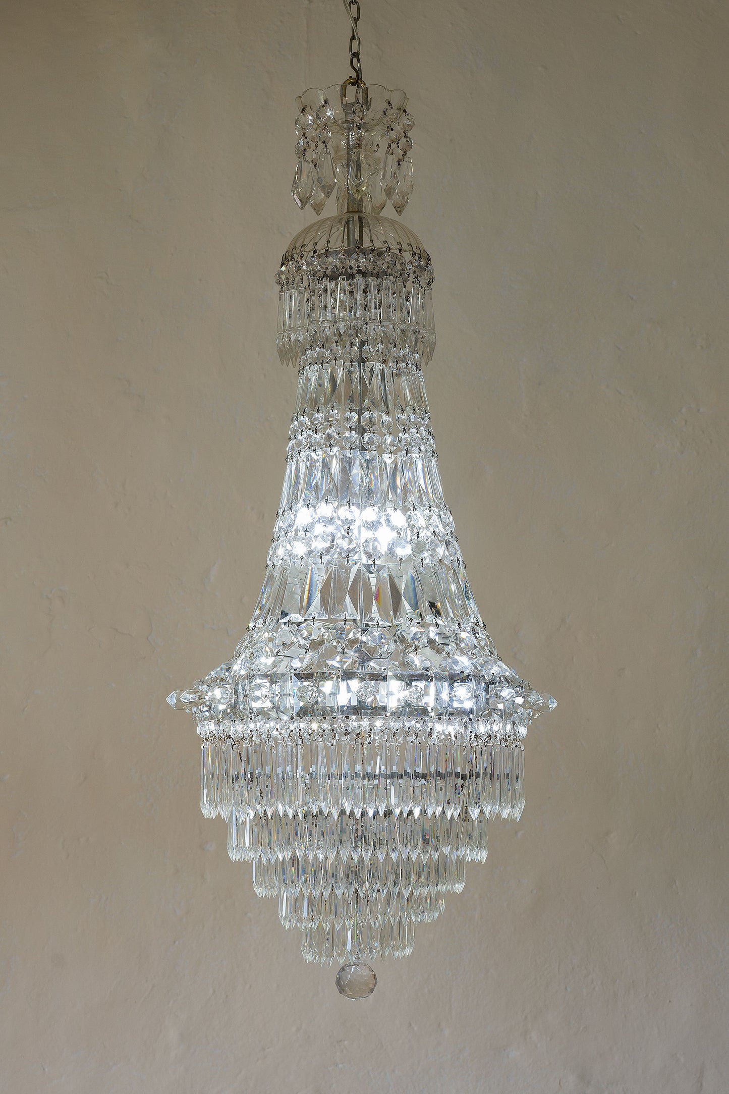 Lampadario con struttura nichelata rivestito da piastre e gocce di cristallo.-Lo Stile Italiano