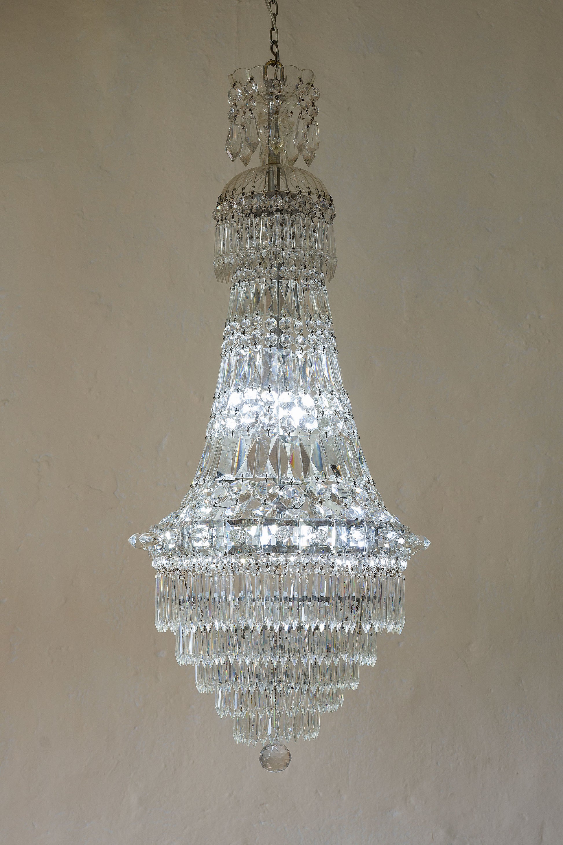 Lampadario con struttura nichelata rivestito da piastre e gocce di cristallo.-Lo Stile Italiano