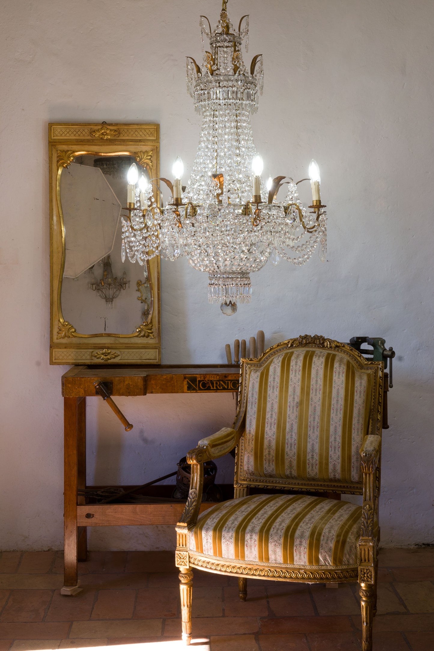 Grande lampadario di cristallo, con specchiera Liberty dorata, poltrona Luigi XV e banco da falegname-Lo Stile ItalianoI,