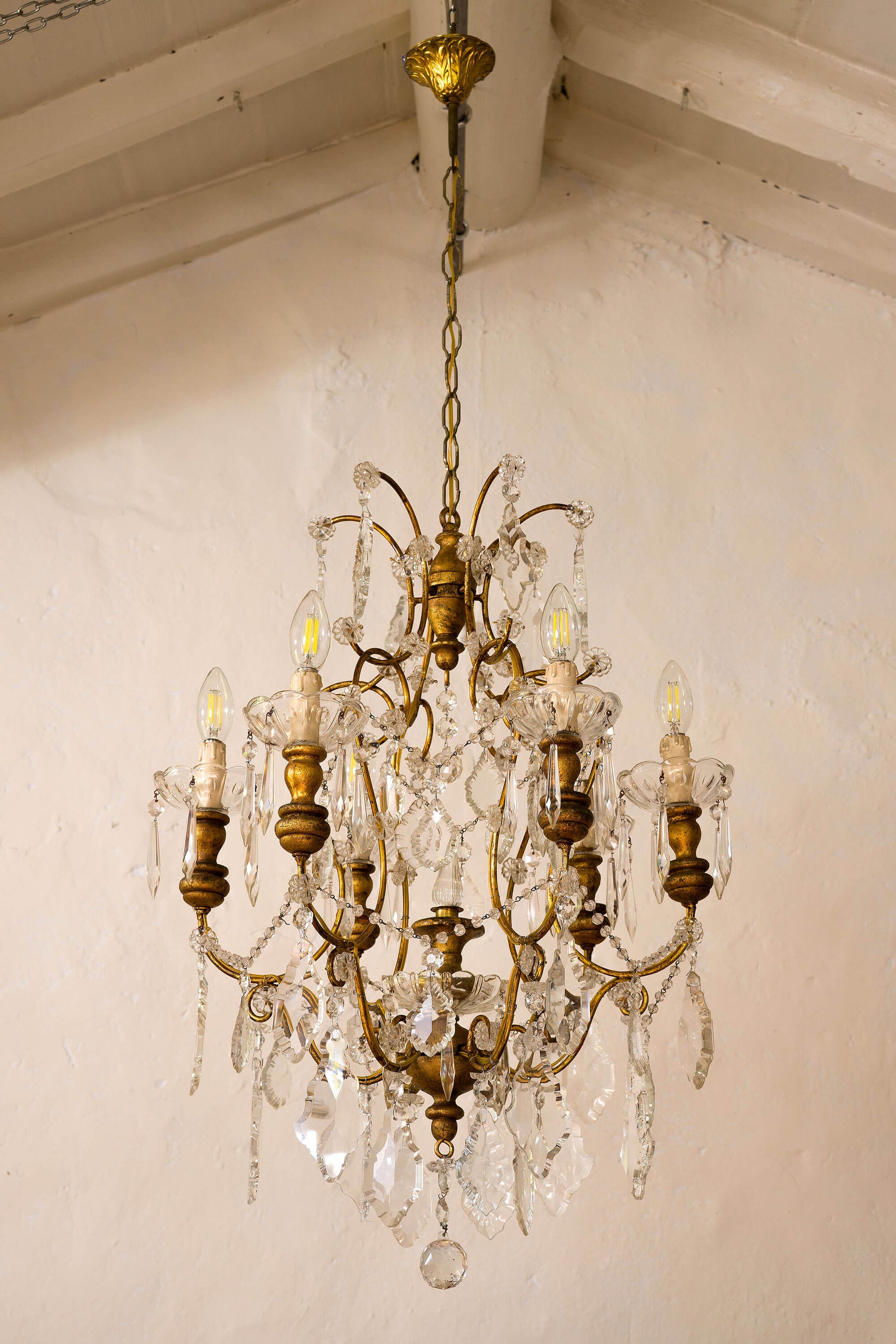 Lampadario a sei luci con base portalampade di legno dorato, realizzato in ferro dorato e gocce di cristallo pendenti-Lo Stile Italiano